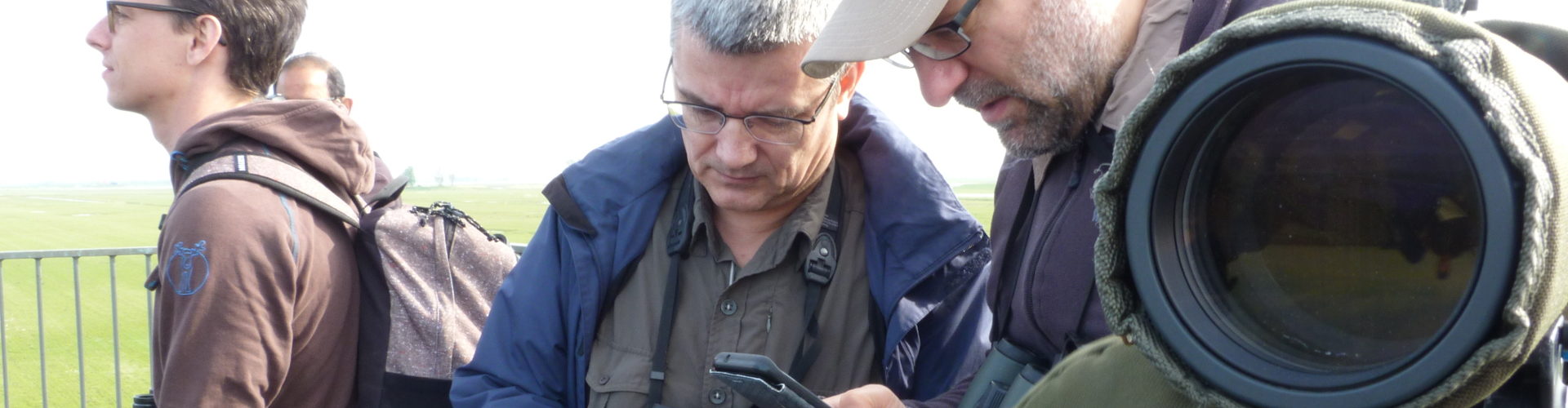 Bird counters with a telescope, cameras, and phones