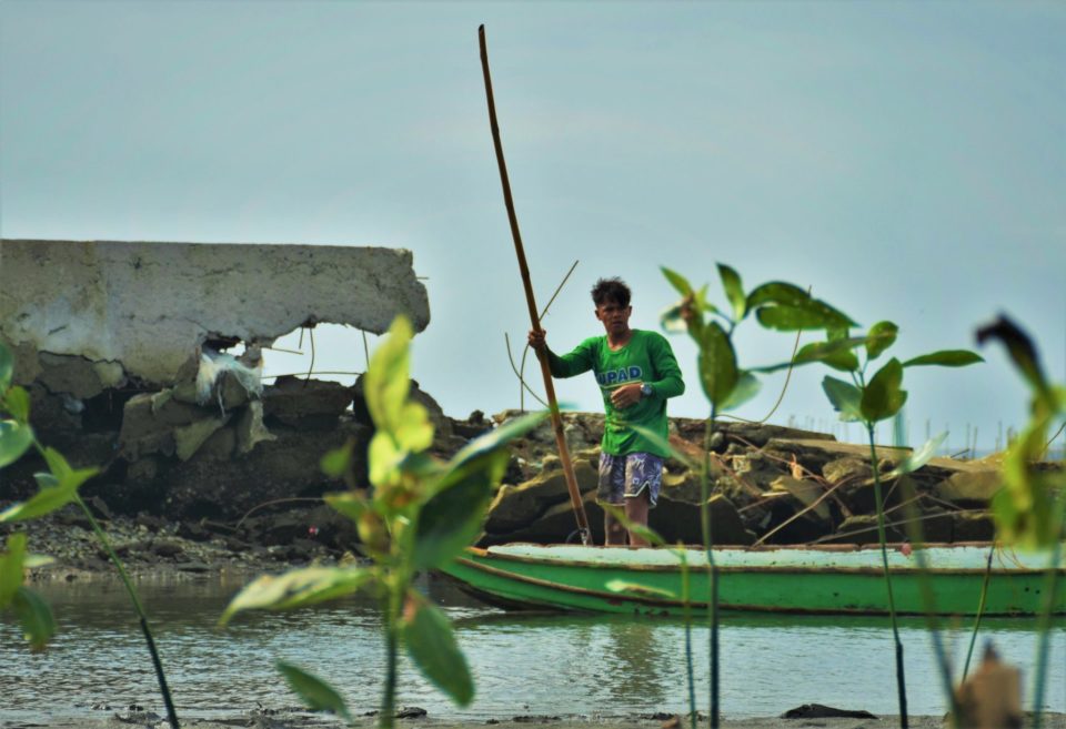 Fisherman rows in front of a dilapidated dike destroyed by tropical storm Nalgae (locally named Typhoon Paeng) that hit the province in late October 2022. The mangrove seedlings planted near the dike are hoped to grow into natural frontiers that would protect Barangay Pamarawan in Bulacan Province.